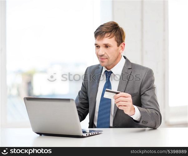 business, online banking, internet shopping concept - smiling man with laptop and credit card in office