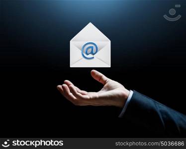 business, online communication and people concept - close up of businessman hand with e-mail message icon over dark background. close up of businessman hand