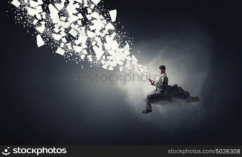 Business online. Young businessman sitting on cloud with mobile phone in hands