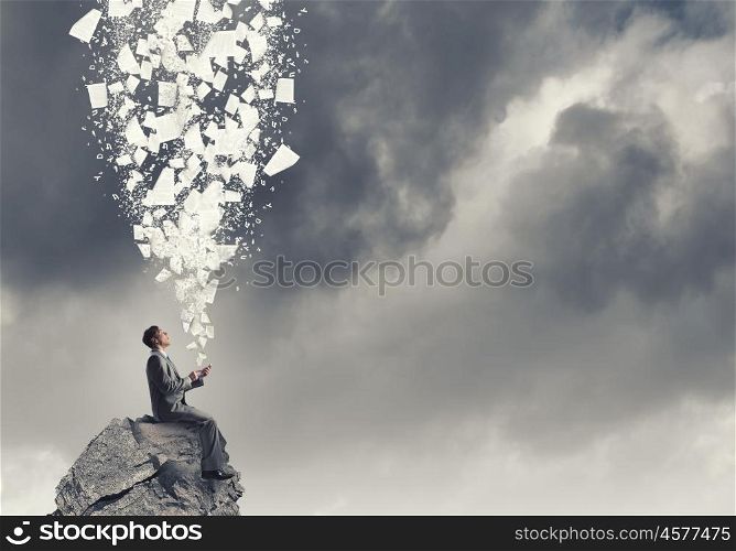 Business online. Young businessman sitting on rock top with mobile phone in hand