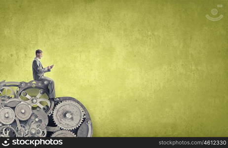 Business online. Young businessman sitting on steps with mobile phone in hands