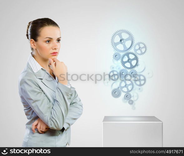 Business organization. Image of thoughtful businesswoman looking at gears. Business structure