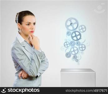 Business organization. Image of thoughtful businesswoman looking at gears. Business structure