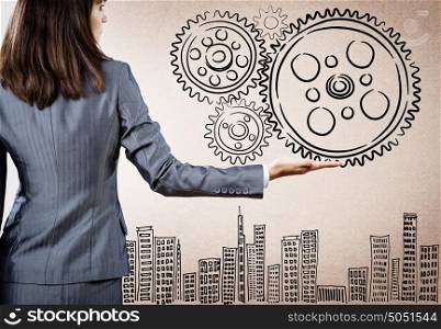 Business organization. Rear view of businesswoman holding gears in palm