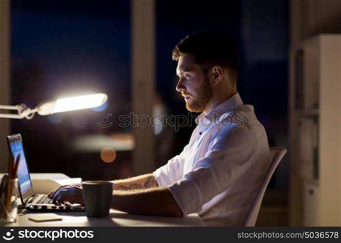 business, overwork, deadline and people concept - man with laptop and coffee working late at night in office. man with laptop and coffee working at night office