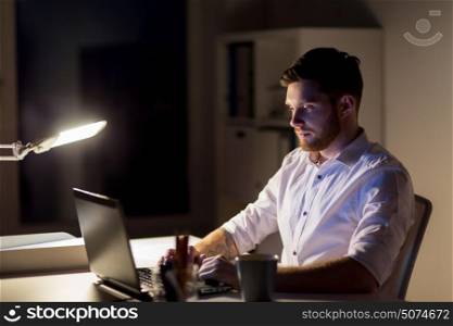 business, overwork, deadline and people concept - man with laptop and coffee working late at night in office. man with laptop and coffee working at night office