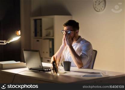 business, overwork, deadline and people concept - tired man with laptop computer working at night office. tired businessman with laptop at night office