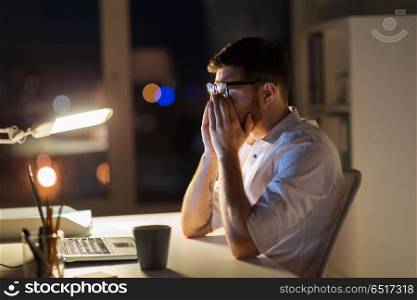 business, overwork, deadline and people concept - tired man with laptop computer working at night office. tired businessman with laptop at night office. tired businessman with laptop at night office