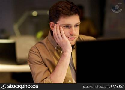 business, overwork, deadline and people concept - tired or bored man on table at night office. tired or bored man on table at night office