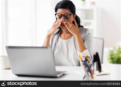 business, overwork, deadline, vision and people concept - tired businesswoman in glasses working at office and rubbing eyes. businesswoman rubbing tired eyes at office