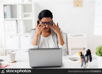 business, overwork, deadline, vision and people concept - tired businesswoman in glasses working at office and rubbing eyes. businesswoman rubbing tired eyes at office