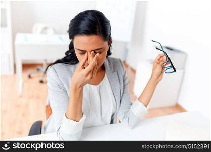 business, overwork, deadline, vision and people concept - tired businesswoman with glasses working at office and rubbing eyes. businesswoman rubbing tired eyes at office