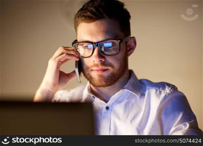 business, overwork, people, deadline and technology concept - businessman in glasses with laptop computer calling on smartphone at night office. businessman calling on smartphone at night office