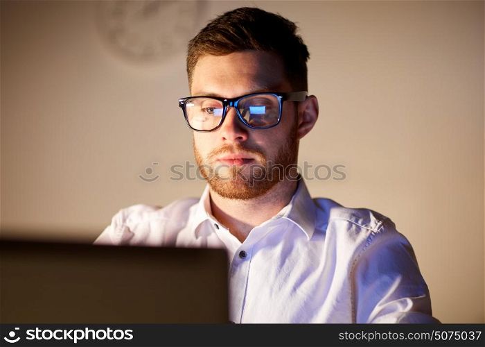 business, overwork, people, deadline and technology concept - businessman in glasses with laptop computer thinking at night office. businessman in glasses with laptop at night office