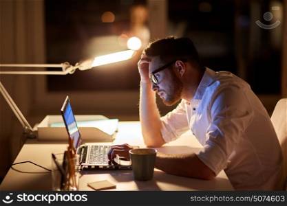 business, overwork, people, deadline and technology concept - stressed businessman in glasses with laptop computer typing at night office. businessman typing on laptop at night office