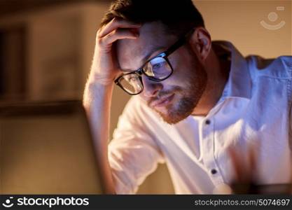 business, overwork, people, deadline and technology concept - stressed businessman in glasses with laptop computer thinking at night office. businessman with laptop thinking at night office