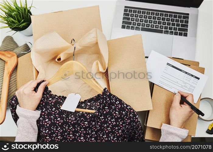 Business owner packing online order to delivery to customer. Preparing parcel box with clothes product from online shop