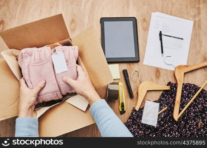 Business owner packing online order to delivery to customer. Preparing parcel box with clothes product from online shop