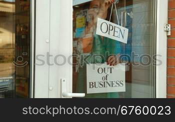 Business owner puts up Out Of Business sign on door of her store