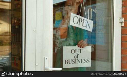 Business owner puts up Out Of Business sign on door of her store