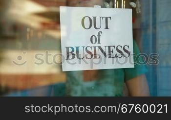 Business owner puts up Out Of Business sign on door of her store, closeup