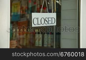 Business owner turns sign from closed to open in front of her store