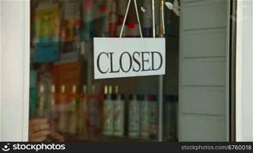 Business owner turns sign from closed to open in front of her store