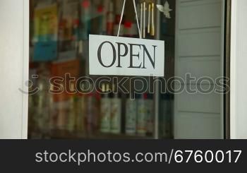 Business owner turns sign from open to closed in front of her store, closeup