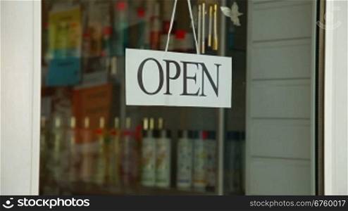Business owner turns sign from open to closed in front of her store, closeup