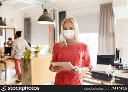 business, pandemic and health concept - businesswoman or creative female office worker wearing face protective medical mask for protection from virus disease with tablet pc computer. female office worker in mask with tablet pc