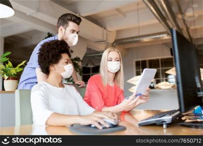 business, pandemic and health concept - creative team wearing face protective medical masks for protection from virus disease with computer and notebook in office. creative team in masks with computer in office
