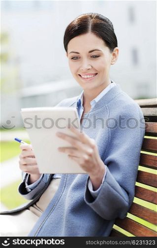 business, paperwork and people concept - young smiling businesswoman reading notes in notepad and sitting on city bench