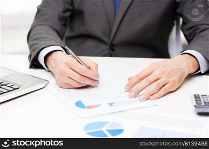 business, paperwork, statistics and people concept - close up of businessman hand with charts and pen in office