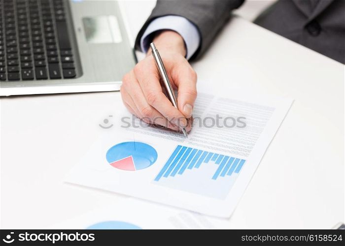 business, paperwork, statistics and people concept - close up of businessman hand with charts and pen in office