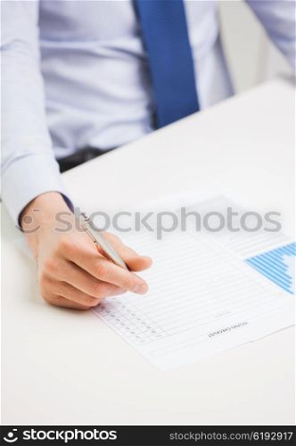 business, paperwork, statistics and people concept - close up of businessman hand with charts and pen filling form in office