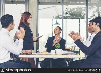 Business Partners clapping hands to a success business woman after complete a deal.
