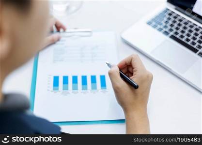Business partners concept a young businessman holding a pen pointing at profit summary of the recent month showing in document forms.