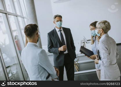 Business partners standing and looking at business results in the office while wearing face masks sa an virus protection