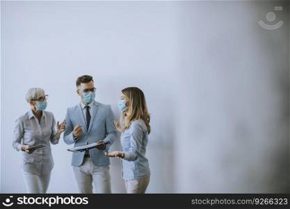 Business partners standing and looking at business results in the office while wearing face masks sa an virus protection