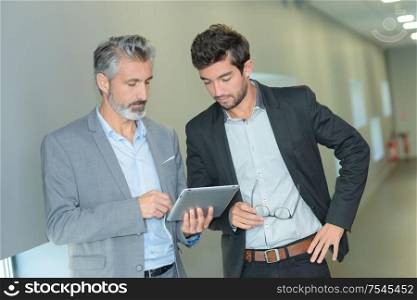 business partners working in hallway with electronic tablet