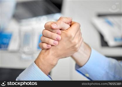 business, partnership and confrontation concept - close up of people arm wrestling at office. close up of hand arm wrestling at office