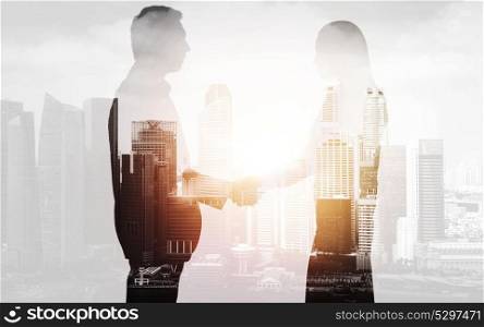 business, partnership and cooperation concept - businessman and businesswoman silhouettes shaking hands over city background. business people shaking hands over city background