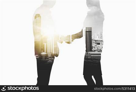 business, partnership and cooperation concept - businessman and businesswoman silhouettes shaking hands over city background. business people shaking hands over city background