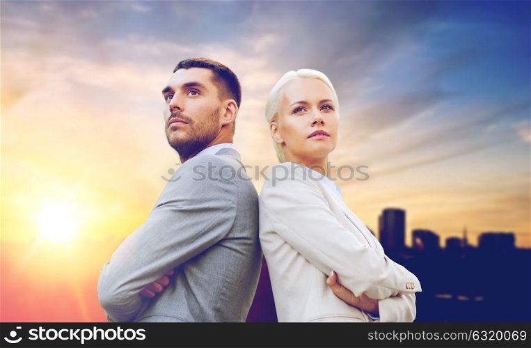 business, partnership and teamwork concept - businessman and businesswoman standing over city background. businessman and businesswoman outdoors