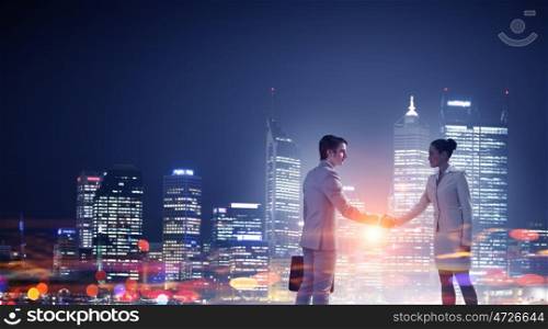 Business partnership as concept. Concept of partnership with business people shaking hands against night city view