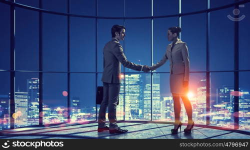 Business partnership as concept. Concept of partnership with business people shaking hands against night city view