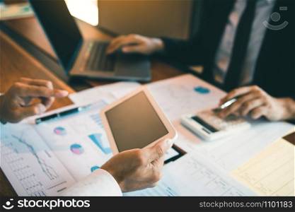 Business partnership coworkers using a tablet to analysis graph company financial budget report and cost work progress and planning for future in office room