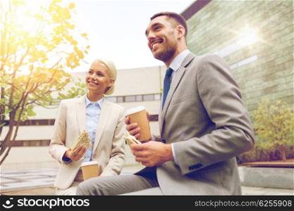 business, partnership, food, drinks and people concept - smiling businessmen with paper cups standing over office building