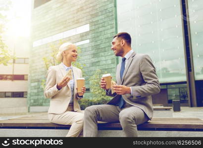 business, partnership, food, drinks and people concept - smiling businessmen with paper cups standing over office building