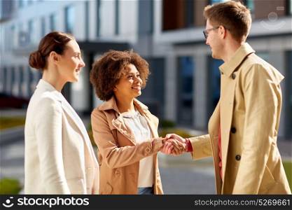 business, partnership, gesture and cooperation concept - happy people shaking hands on city street. happy people shaking hands on city street